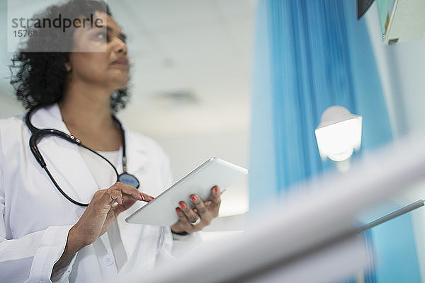 Fokussierte Ärztin mit digitalem Tablet im Krankenhauszimmer