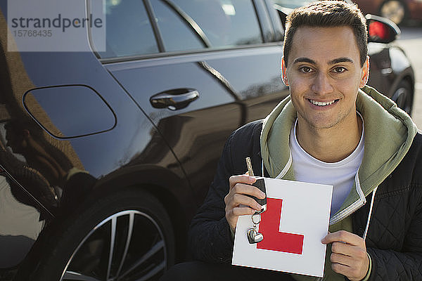 Porträt eines selbstbewussten  glücklichen jungen Mannes mit Führerschein im Auto