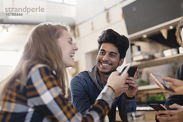 Glückliche junge Erwachsene  die im Café ihr Smartphone benutzen