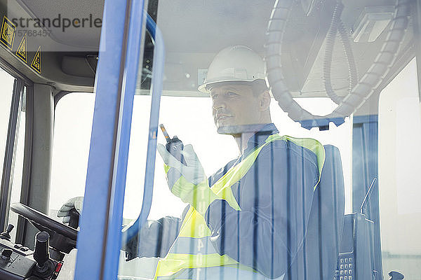 Hafenarbeiter mit Walkie-Talkie bei der Bedienung eines Gabelstaplers