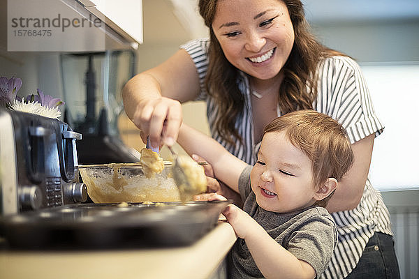 Glückliche Mutter und Kleinkind Tochter backen Muffins in der Küche