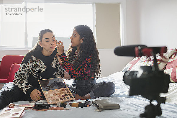 Teenager-Mädchen Vlogging über Make-up-Anwendung auf dem Bett im Schlafzimmer