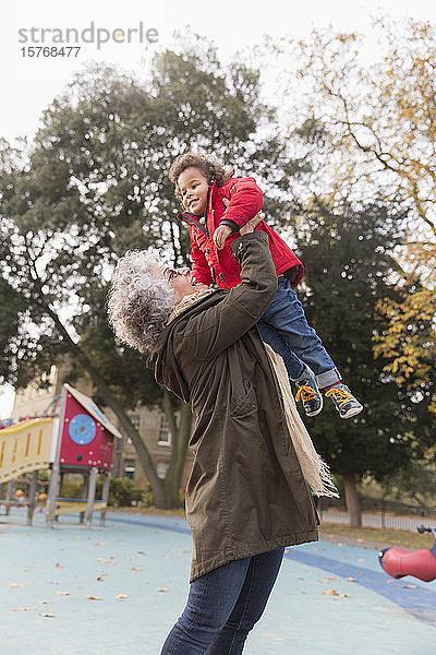 Großmutter hebt ihre Enkelin auf dem Spielplatz hoch