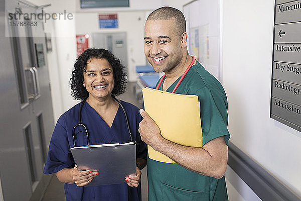 Porträt selbstbewusster Ärzte mit Krankenblatt bei der Visite im Krankenhauskorridor