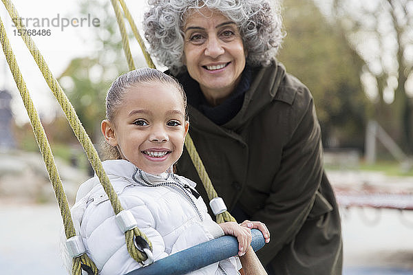 Porträt lächelnd Großmutter und Enkelin spielen auf Schaukel auf dem Spielplatz
