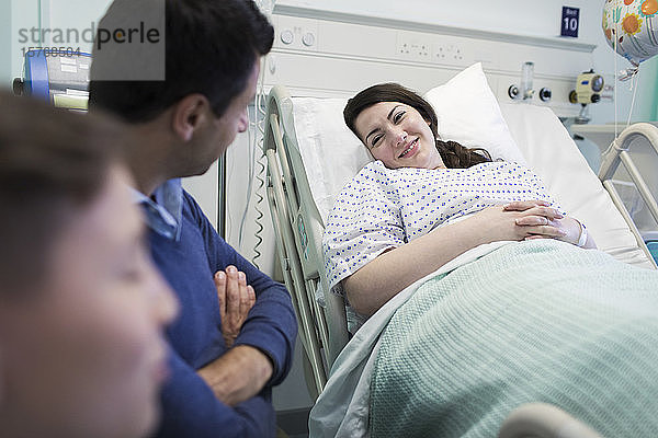 Familie besucht lächelnden Patienten im Krankenhausbett