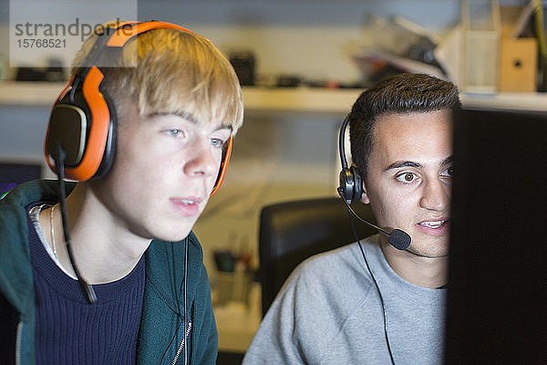 Teenager mit Kopfhörern spielen ein Videospiel am Computer