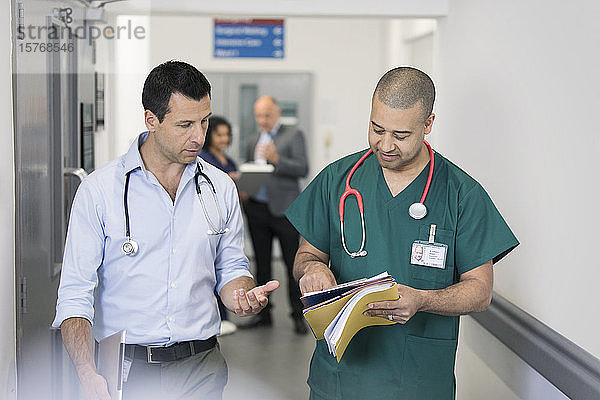 Männlicher Arzt und Chirurg besprechen Krankenakte  machen Visite im Krankenhauskorridor