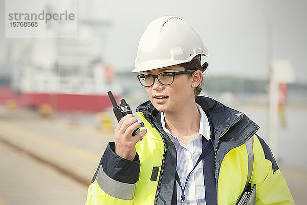 Hafenarbeiterin mit Walkie-Talkie in einer Werft