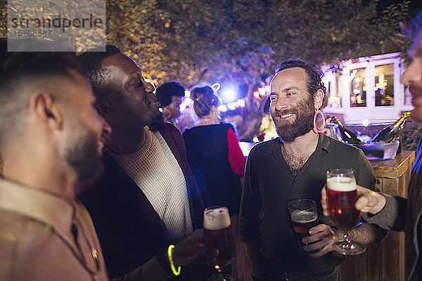 Glückliche männliche Freunde trinken Bier auf einer Gartenparty