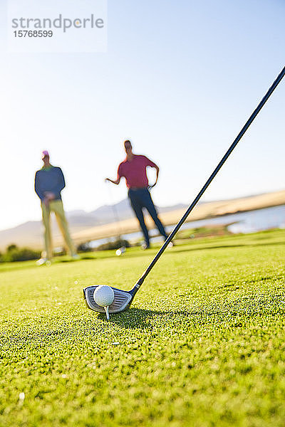 Ein Golfer bereitet sich auf den Abschlag auf einem sonnigen Golfplatz vor