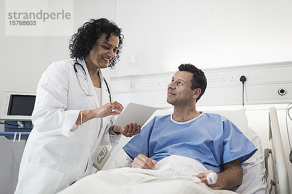 Arzt mit digitalem Tablet bei der Visite  Gespräch mit Patient im Krankenhauszimmer