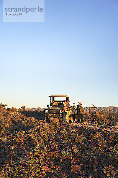 Safari-Gruppe vor einem Geländewagen auf einer sonnigen Wiese