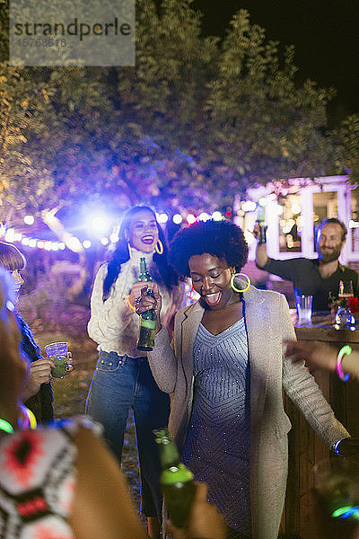 Glückliche Freunde tanzen und trinken auf einer Gartenparty