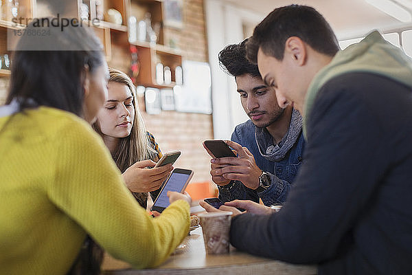 Freunde junger Erwachsener benutzen Smartphones am Kaffeetisch
