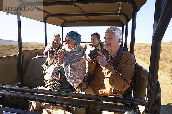 Glückliche Senioren mit Fernglas und Kamera auf Safari im Geländewagen