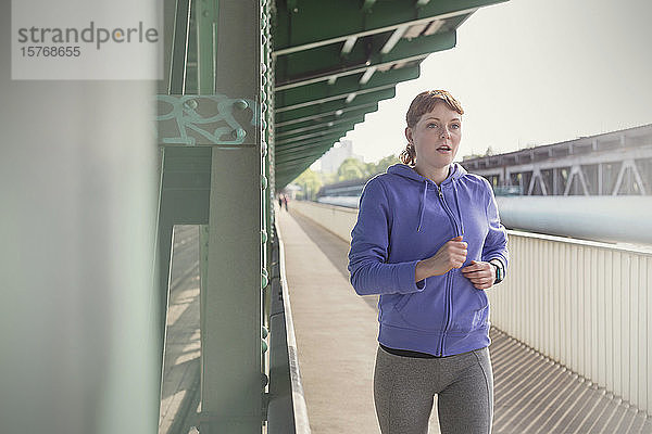 Engagierte junge Frau läuft auf dem sonnigen Bahnsteig