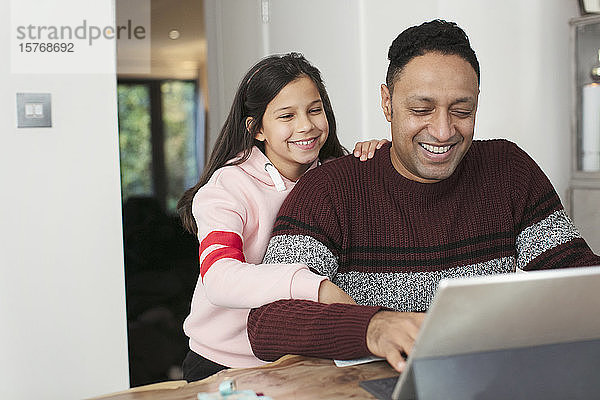 Lächelnder Vater und Tochter benutzen ein digitales Tablet am Tisch