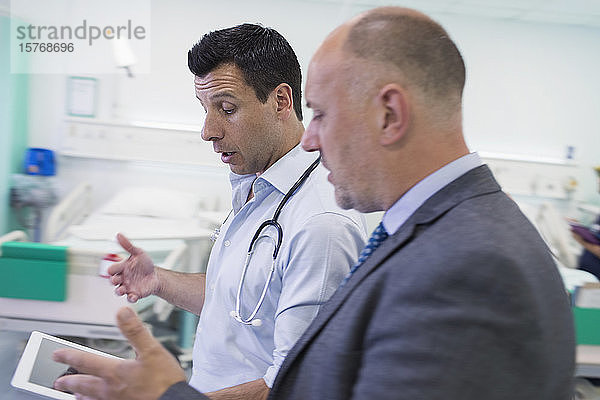 Männliche Ärzte mit digitalem Tablet bei der Visite  Beratung im Krankenhauszimmer