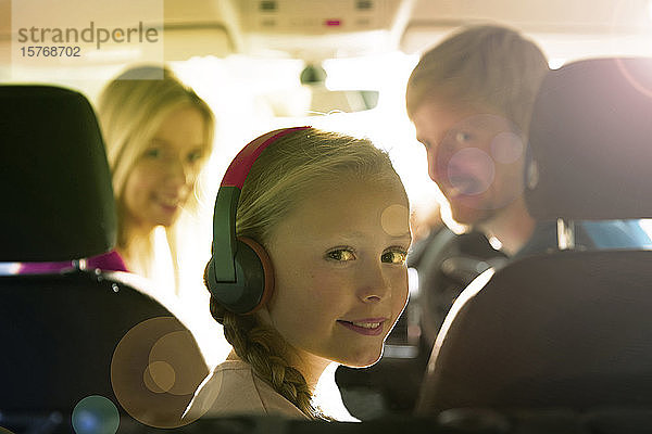 Portrait lächelndes Mädchen mit Kopfhörern auf dem Rücksitz eines Autos