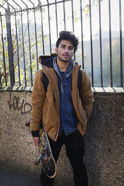 Porträt selbstbewusster junger Mann mit Skateboard