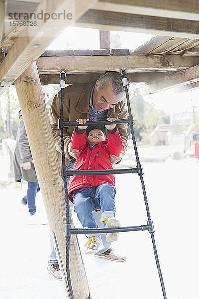 Großvater spielt mit Enkel auf Spielplatzleiter