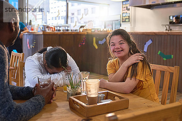 Glückliche junge Frau mit Down-Syndrom lacht mit Freunden in einem Café