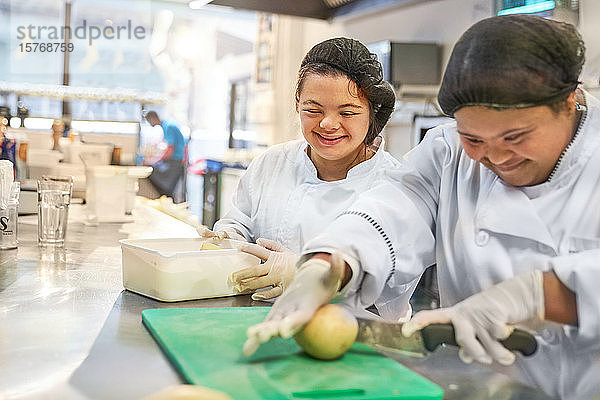 Glückliche junge Frau mit Down-Syndrom beim Kochen im Restaurant