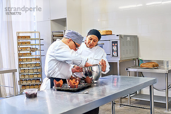 Koch und Student mit Down-Syndrom backen Muffins in der Küche