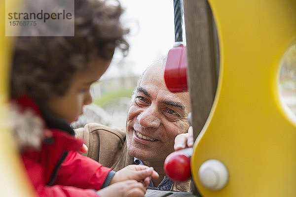 Lächelnder Großvater spielt mit Enkel auf dem Spielplatz