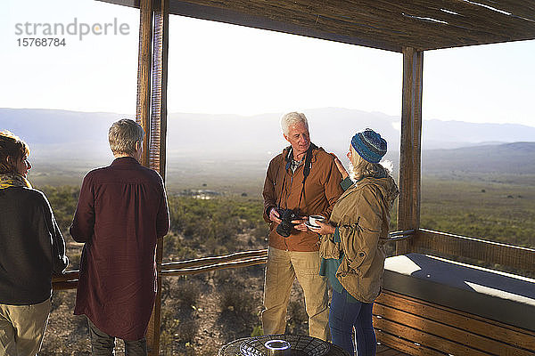 Älteres Paar mit Kamera und Tee auf dem sonnigen Balkon einer Safari-Lodge