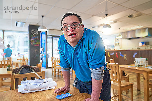Porträt eines selbstbewussten jungen Mannes mit Down-Syndrom bei der Arbeit in einem Cafe