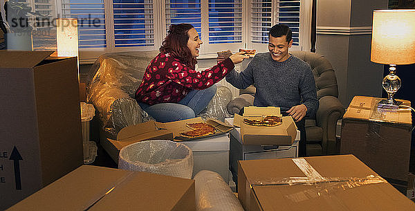 Ein glückliches Paar macht eine Pause vom Umzug und isst Pizza