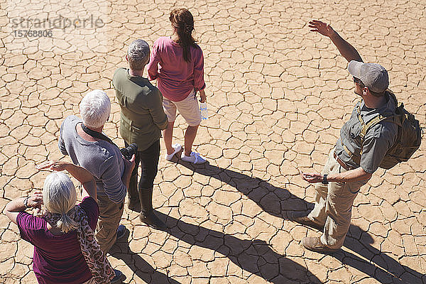 Safari-Reiseleiter im Gespräch mit der Gruppe auf der sonnigen  rissigen Erde