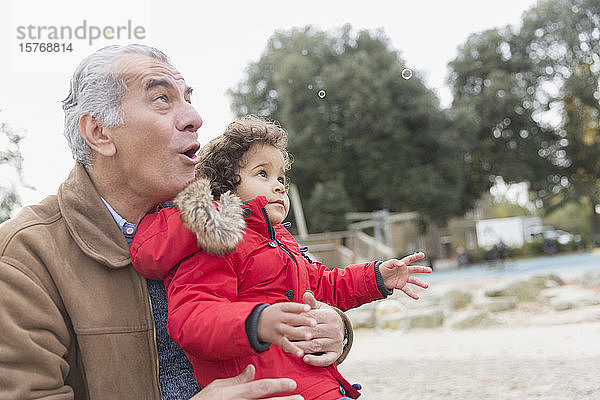 Großvater und Kleinkind-Enkel spielen mit Seifenblasen im Park
