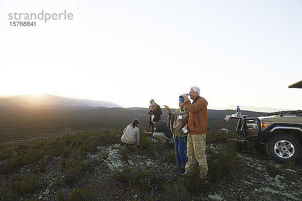 Safari-Gruppe trinkt Tee und genießt den Blick auf die Landschaft bei Sonnenaufgang