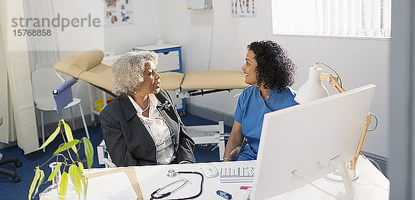 Ärztin im Gespräch mit einem älteren Patienten in einer Arztpraxis