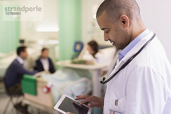 Männlicher Arzt mit digitalem Tablet bei der Visite in einer Krankenstation