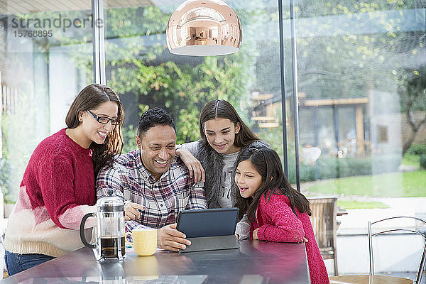 Glückliche Familie mit digitalem Tablet am Küchentisch