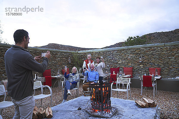 Ältere Freunde mit Wein posieren für ein Foto an der Feuerstelle auf der Terrasse