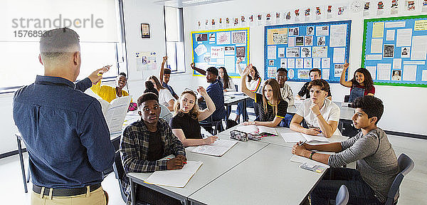 Gymnasiallehrer fordert Schüler mit erhobenen Händen im Klassenzimmer auf