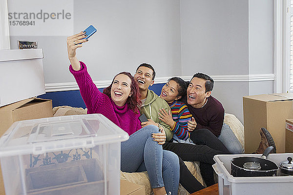 Glückliche Freunde machen eine Pause vom Umzug und machen ein Selfie auf dem Sofa