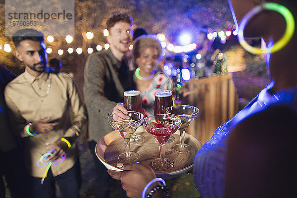 Frau serviert Freunden bei einer Gartenparty Cocktails