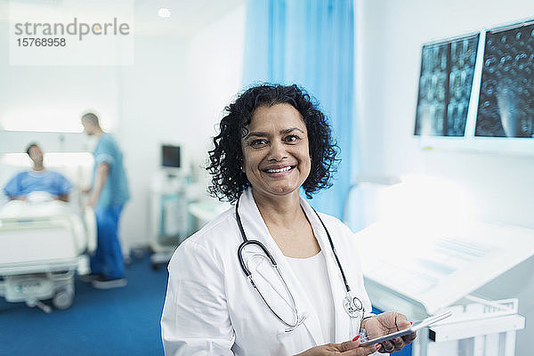 Porträt einer lächelnden  selbstbewussten Ärztin  die ein digitales Tablet in einem Krankenhauszimmer benutzt
