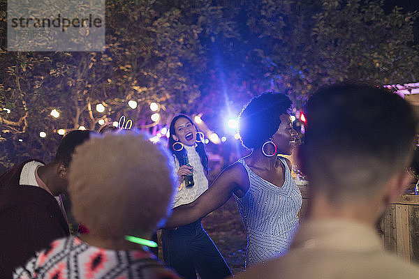 Verspielte Freunde trinken und tanzen auf einer Gartenparty