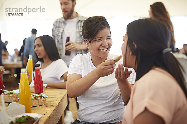 LÃ?chelnde Frau fÃ?ttert ihre Freundin mit Essen auf dem Bauernmarkt