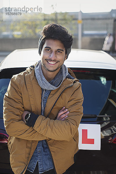 Porträt eines selbstbewussten jungen Mannes mit Führerschein  der sich an ein Auto lehnt