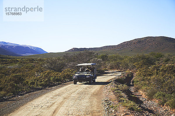Safari-Geländewagen auf sonniger  unbefestigter Straße in Südafrika