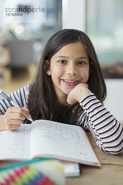 Porträt selbstbewusstes  lächelndes Mädchen bei den Hausaufgaben
