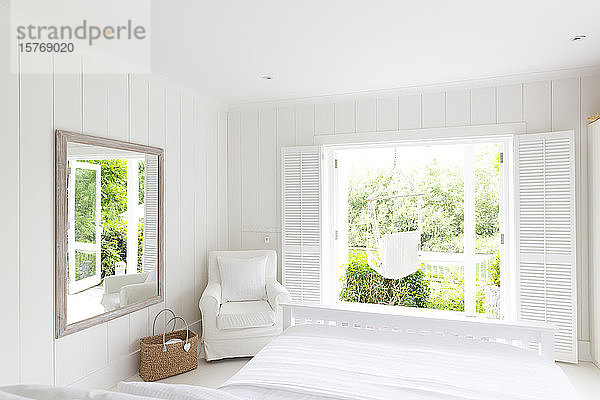 Weißes  ruhiges Musterhaus mit Schlafzimmer  das zur sonnigen Terrasse mit Hängematte führt